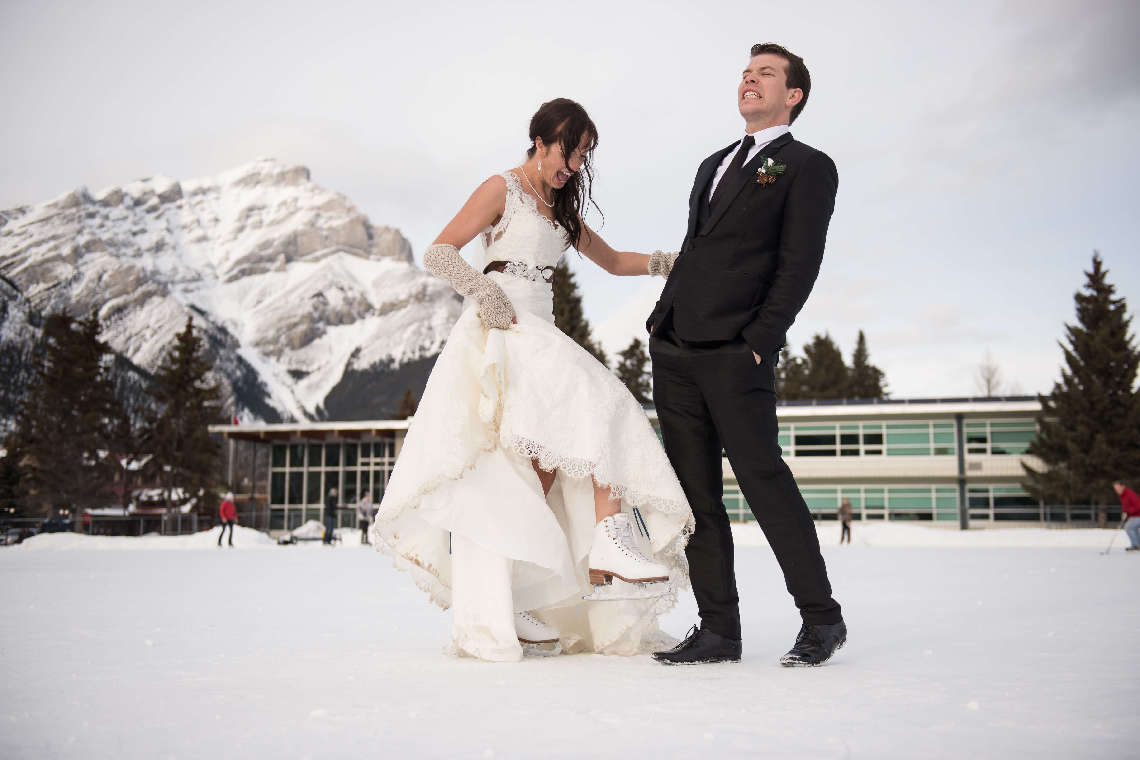 Breanna & Tom's Wedding Photo, they are standing outside in the snow, Breanna is wearing skates.