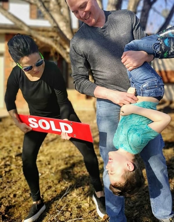 Couple and their child holding a sold sign